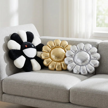 Decorative flower-shaped pillows in black, gold, and silver on a gray sofa.