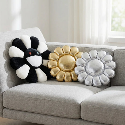 Decorative flower-shaped pillows in black, gold, and silver on a gray sofa.