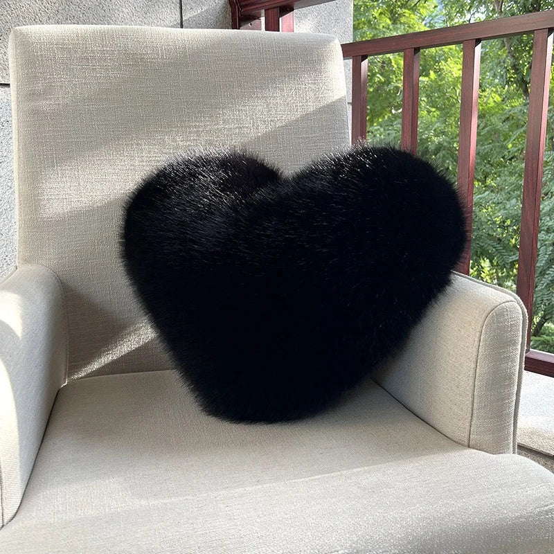 Black heart-shaped pillow on a beige chair outdoors