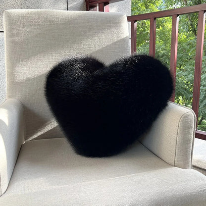 Black heart-shaped pillow on a beige chair outdoors