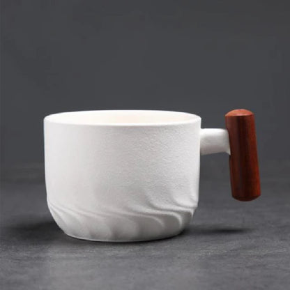 White marbled ceramic mug with a wooden handle on a dark gray background