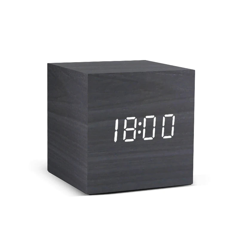 Black cube-shaped digital clock with white LED display on a white background
