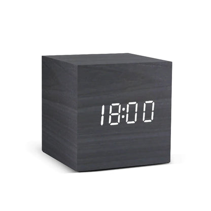Black cube-shaped digital clock with white LED display on a white background