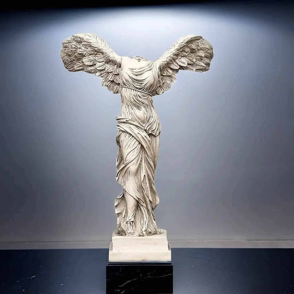 Statue of a winged figure on a dark base against a gray background