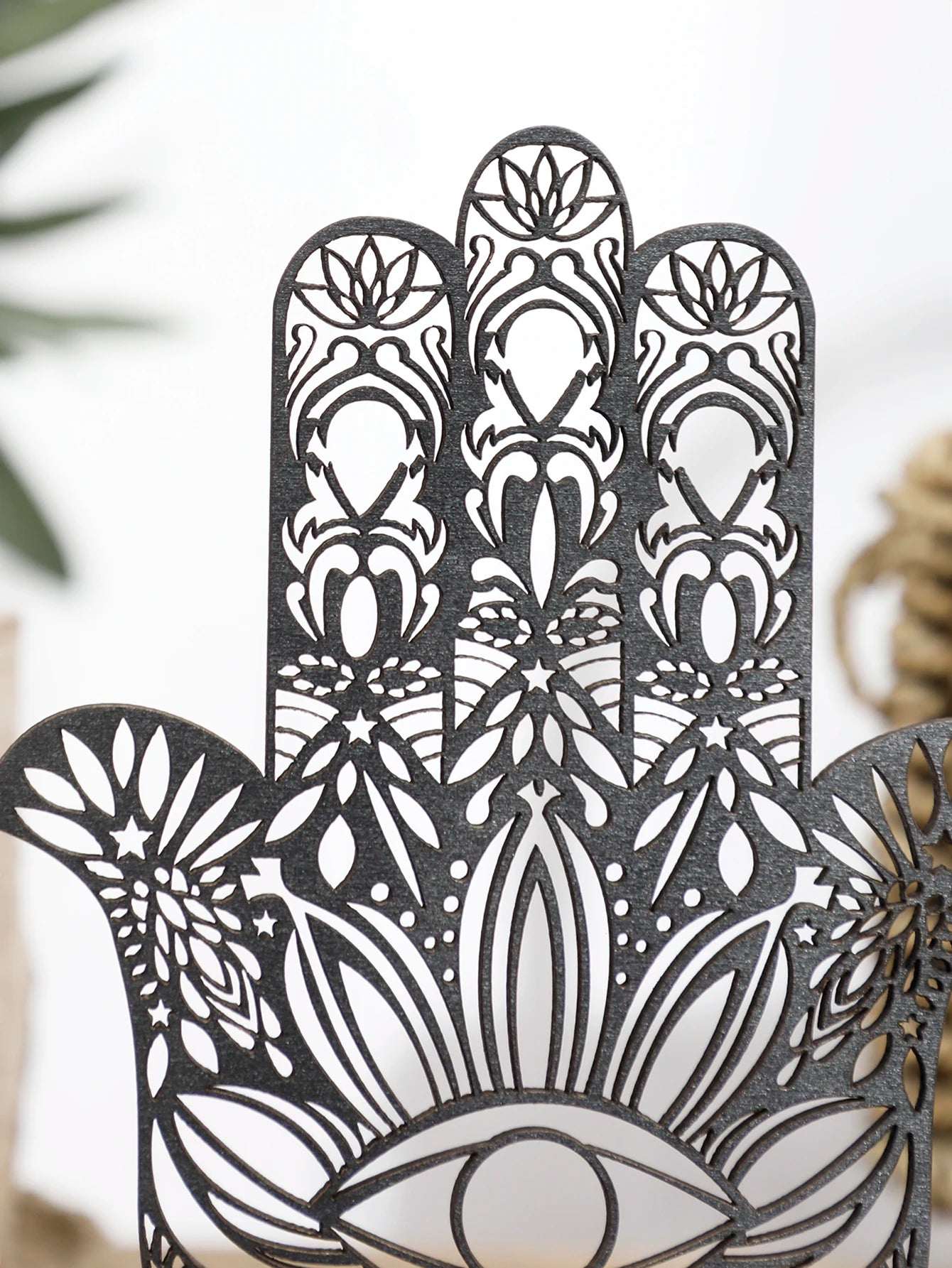 Decorative metal Hamsa hand with intricate patterns on a blurred natural background