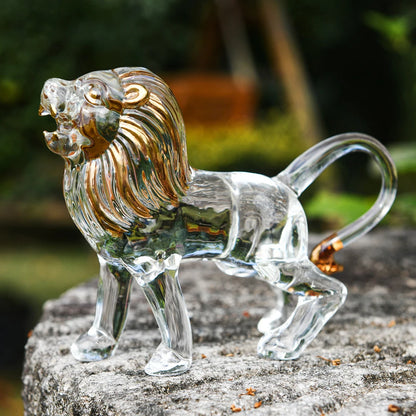 Clear glass lion figurine with gold accents on a stone surface