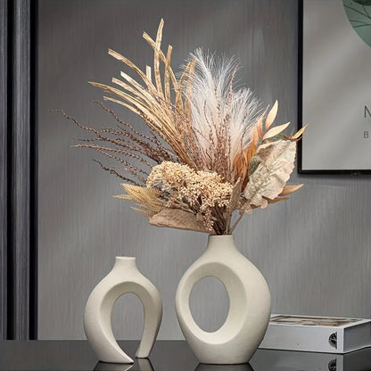 Two white ceramic vases with dried plants on a dark surface.