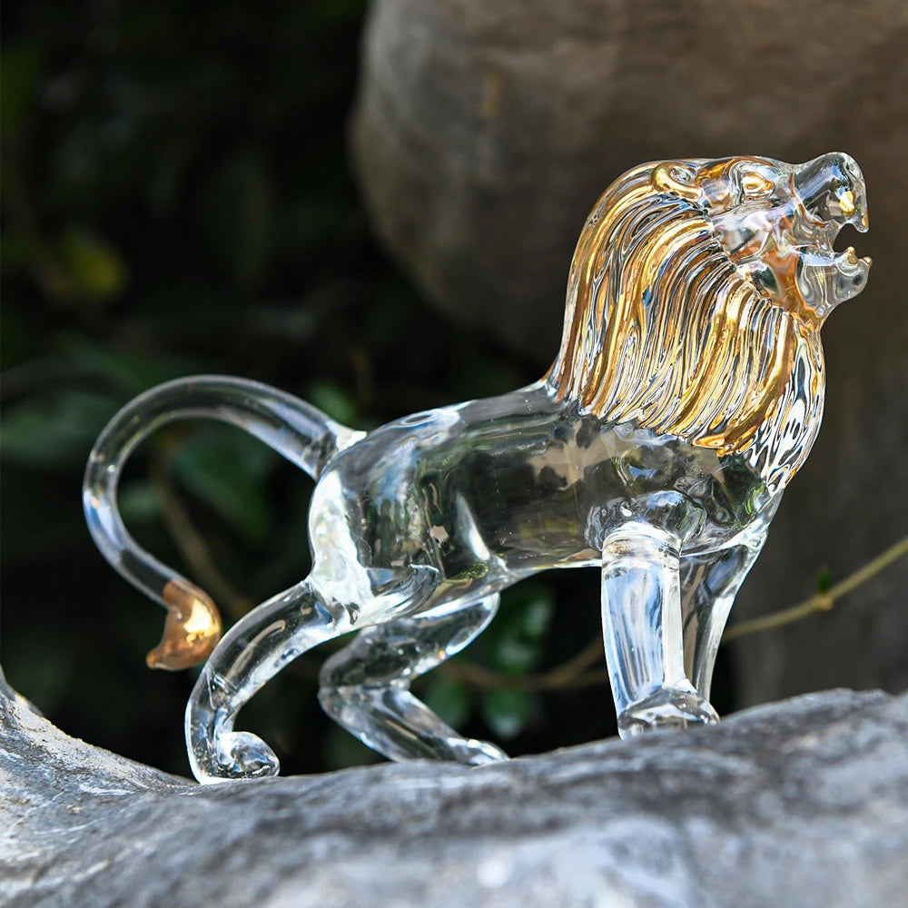 Clear glass lion figurine on a natural stone surface with blurred greenery in the background