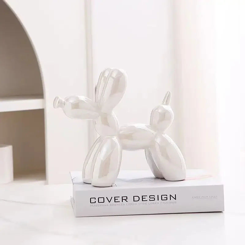 White ceramic balloon dog sculpture on a book with a blurred background