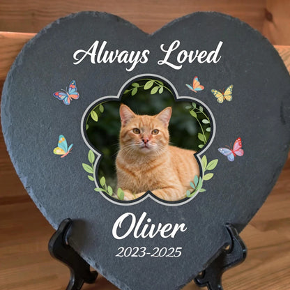 Heart-shaped slate plaque with a cat photo, 'Always Loved Oliver 2023-2025' text, and butterflies on a wooden background.