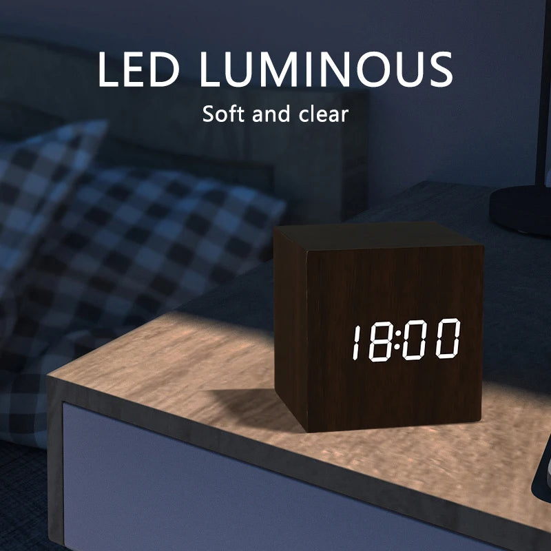 Digital clock displaying the time '18:00' on a wooden surface with a blurred background.