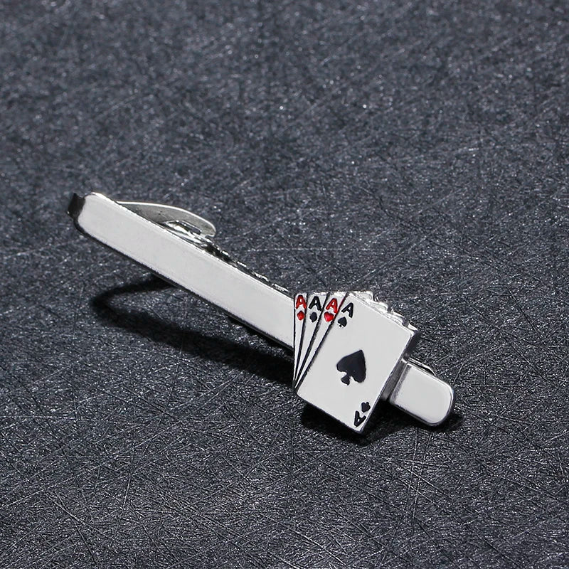 Silver tie clip with playing card design on a textured gray surface
