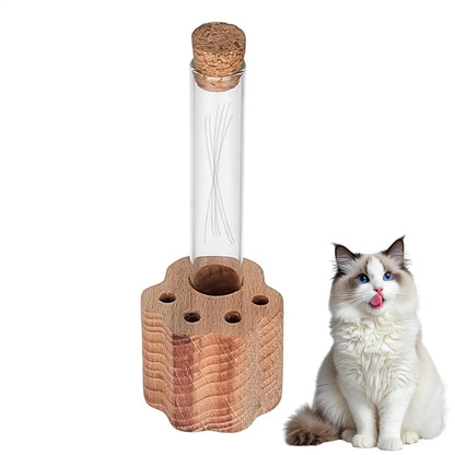 Clear glass bottle with cork lid on a wooden base next to a white and brown cat.