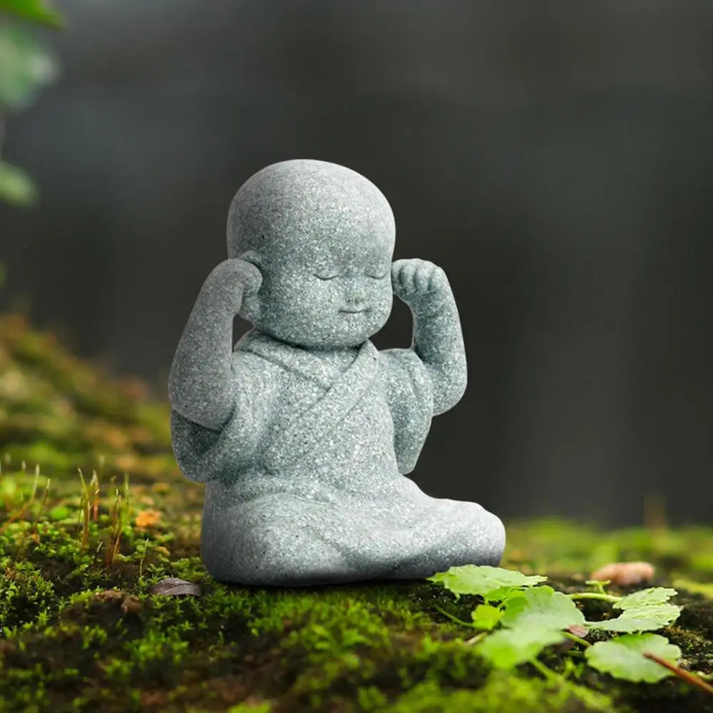 Stone statue of a child in a meditative pose on a mossy surface
