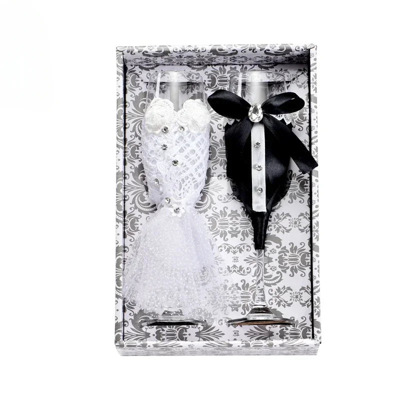 Two figurines, one in a white dress and the other in a black suit with a bow tie, in a decorative box.