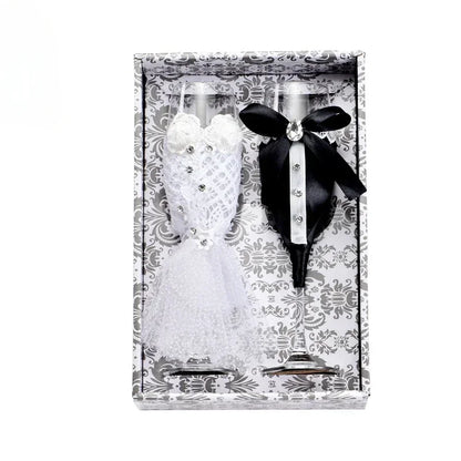 Two figurines, one in a white dress and the other in a black suit with a bow tie, in a decorative box.