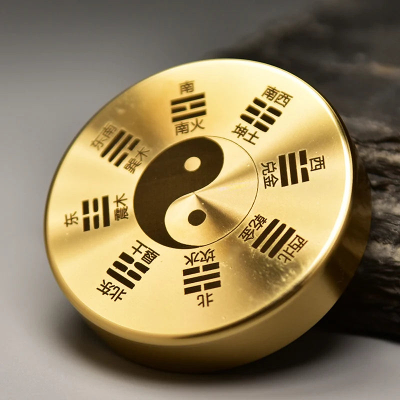 Gold circular object with yin-yang symbol and Chinese characters on a textured surface