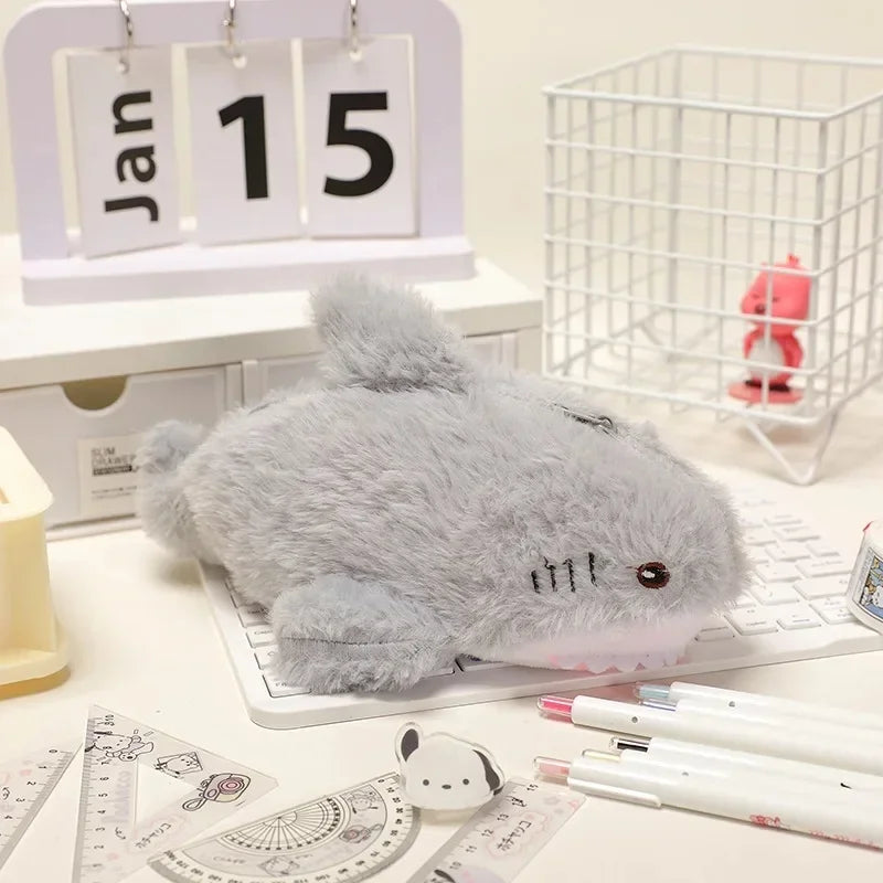 Gray plush mouse on a desk with stationery items and a calendar in the background