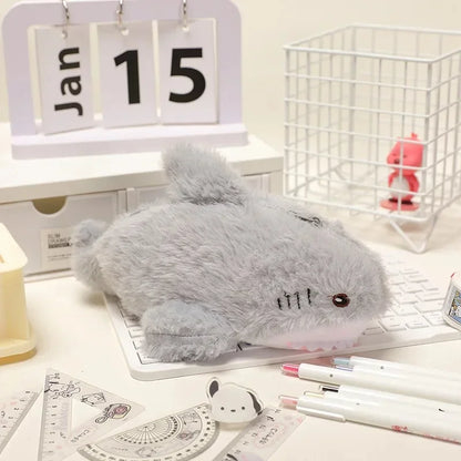 Gray plush mouse on a desk with stationery items and a calendar in the background