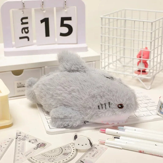 Gray plush mouse on a desk with stationery items and a calendar in the background