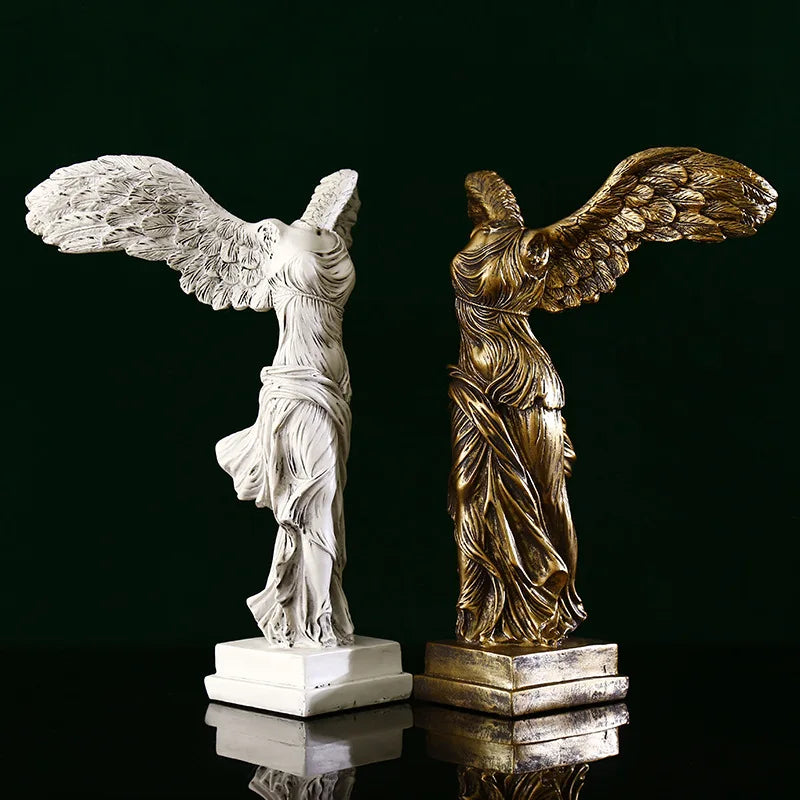 Two statues, one white and one gold, on a reflective surface with a dark background