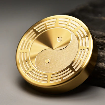 Gold circular object with yin yang symbol on a dark background