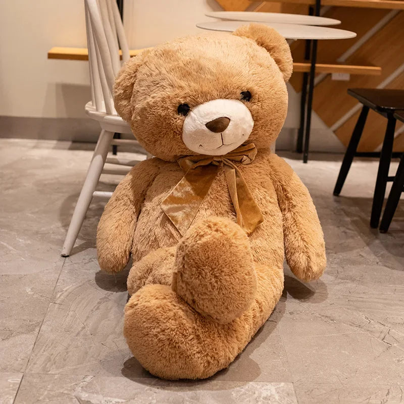 Large teddy bear with a bow tie on a stone floor.