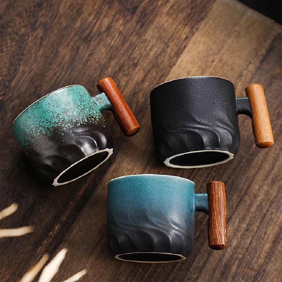Three ceramic mugs with wooden handles on a wooden surface