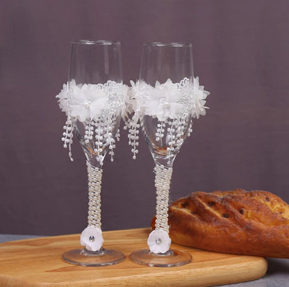 Two decorated wine glasses on a wooden board with bread in the background