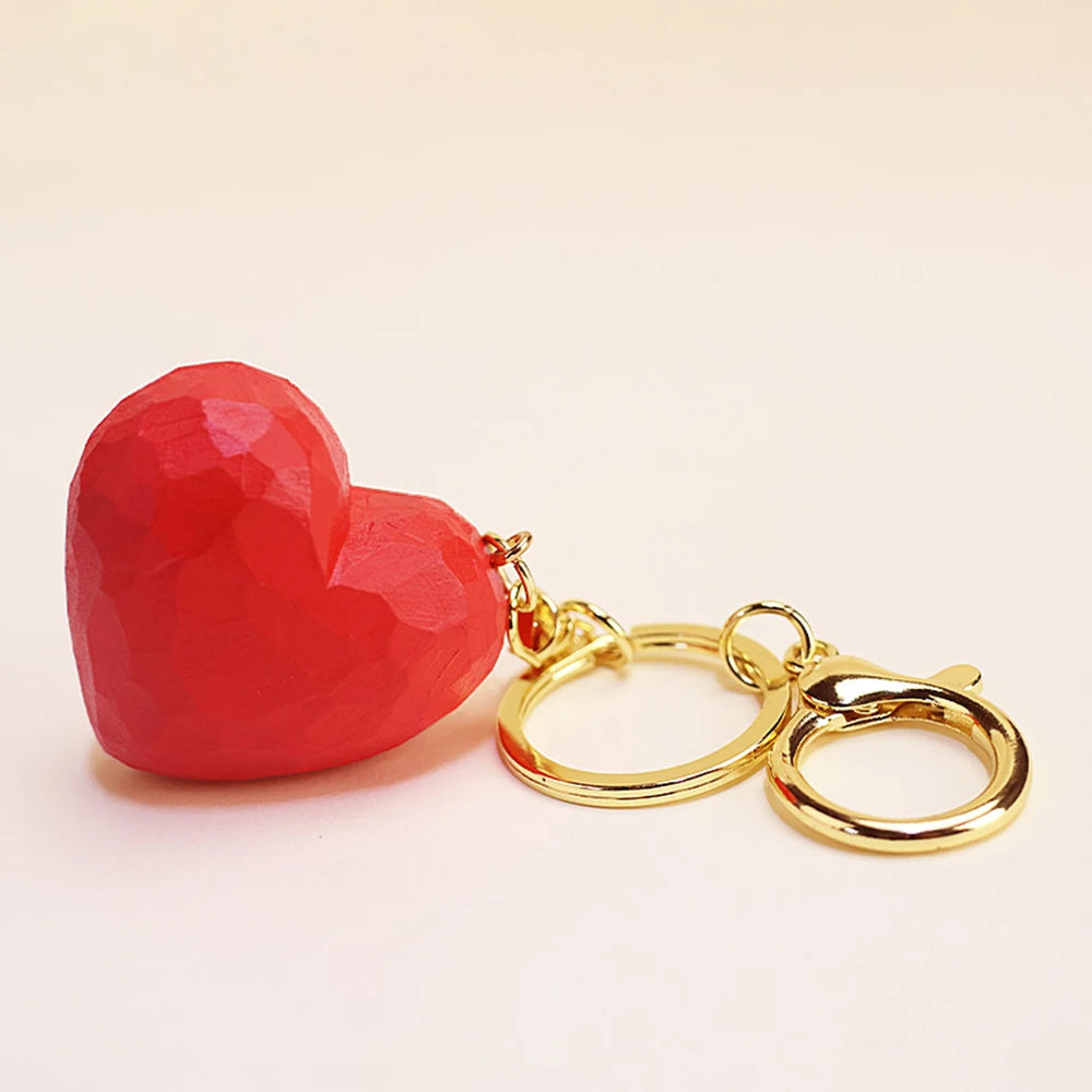 Red heart-shaped keychain with gold rings on a beige background