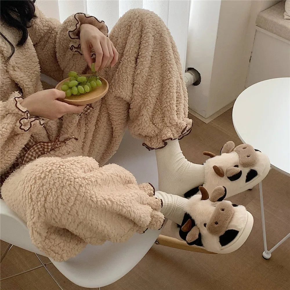 Person wearing fluffy pajamas and cow-themed slippers, sitting on a chair with a bowl of grapes.
