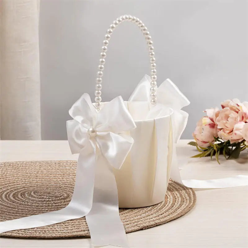 White handbag with pearl handle and large bow on a light surface with flowers in the background