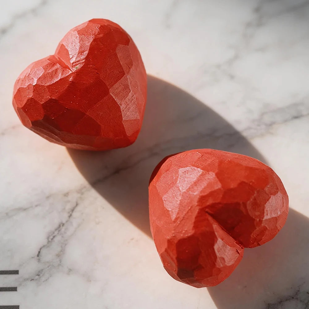 Two red heart-shaped objects on a marble surface