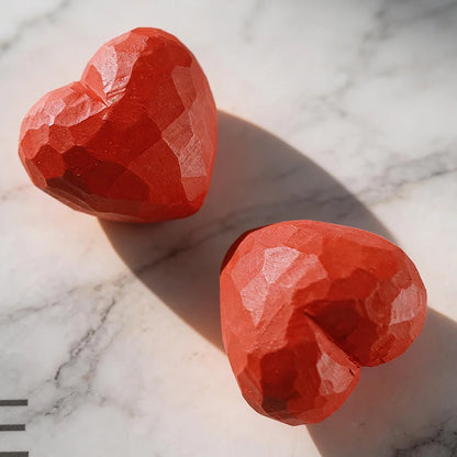 Two red heart-shaped objects on a marble surface