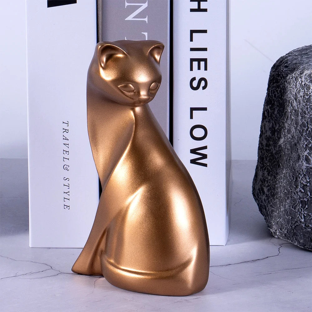 Gold cat-shaped object on a marble surface with books in the background