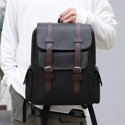 Gray backpack with brown straps held by a person wearing a white shirt.
