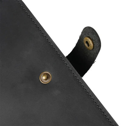 Close-up of a black leather product with gold rivets on a white background
