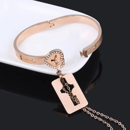 Rose gold bracelet with heart-shaped clasp and cross pendant on a black background