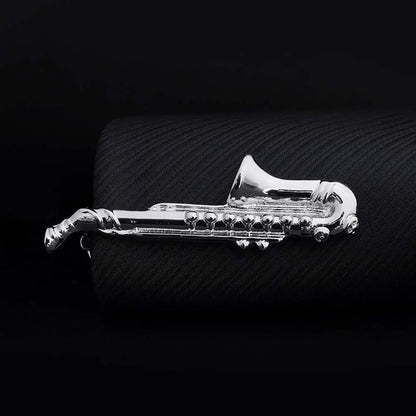 Silver saxophone-shaped object on a textured black surface
