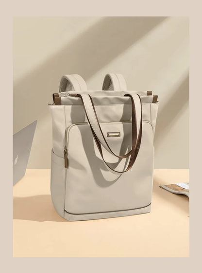 Light gray backpack with brown straps on a beige surface