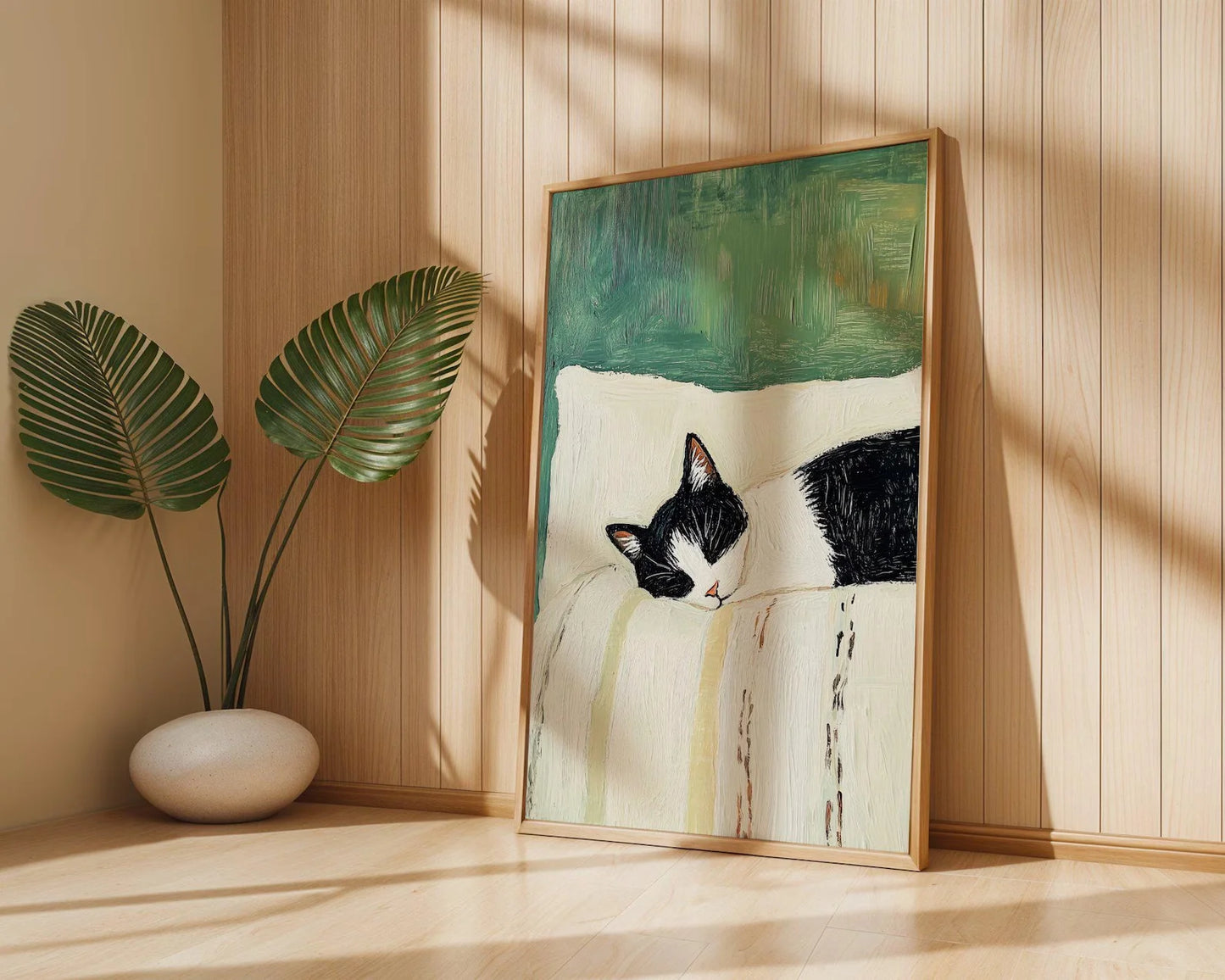 Framed artwork of a black and white cat on a wooden shelf with a plant in the background