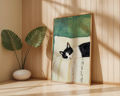 Framed artwork of a black and white cat on a wooden shelf with a plant in the background