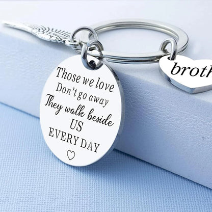 Silver keychain with engraved message on a light blue background