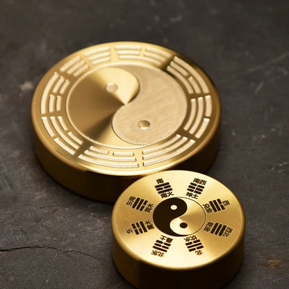 Two gold discs with yin yang symbol on a dark textured surface