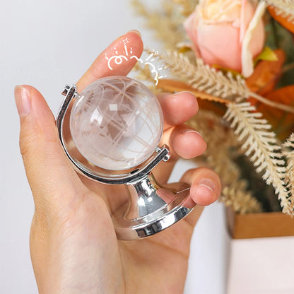 Hand holding a small crystal ball with a silver stand against a blurred floral background