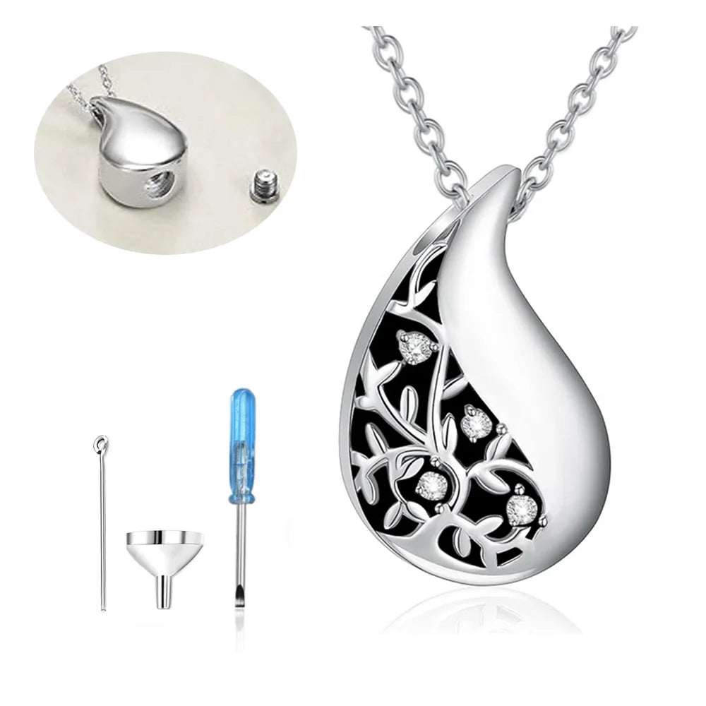 Silver teardrop-shaped pendant with intricate design on a white background, accompanied by tools.