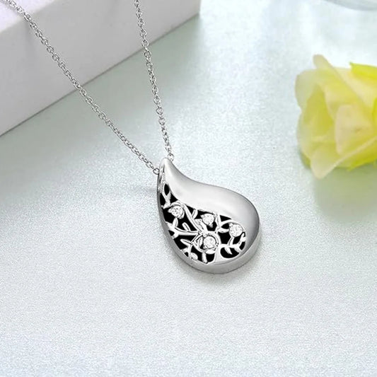 Silver teardrop-shaped pendant necklace on a light gray background with a yellow flower.
