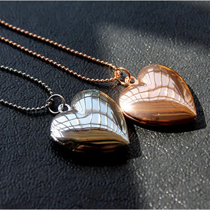 Two heart-shaped pendants on chains against a dark background