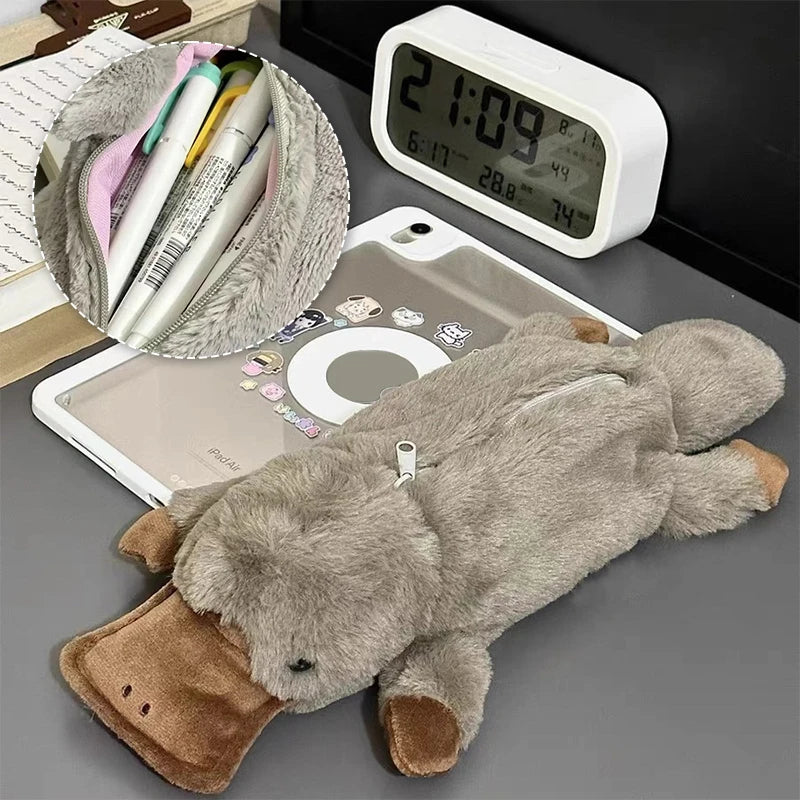 Plush toy elephant on a desk with a digital clock, tablet, and stationery items.