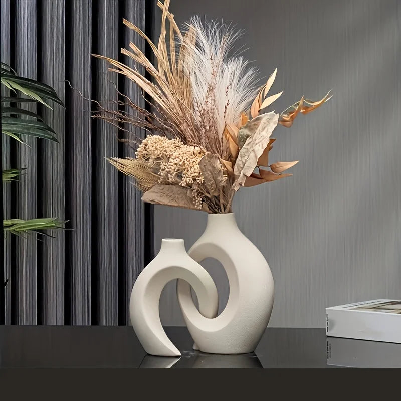 Decorative vase with dried flowers on a reflective surface with a gray curtain background
